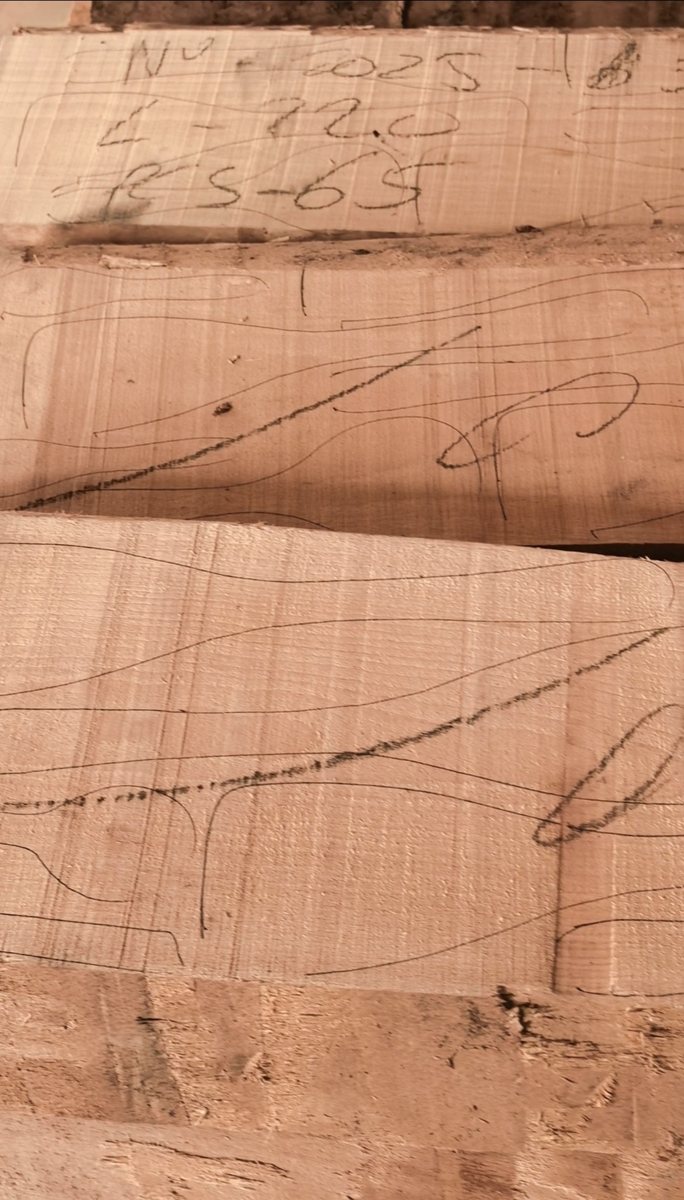 Hand-drawn spoon outlines on solid wood boards before traditional cutting.